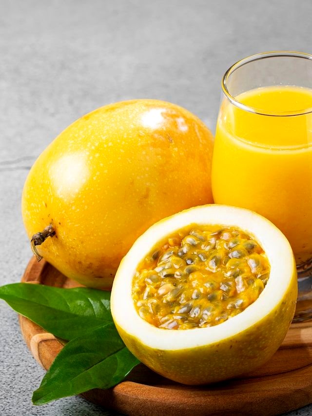 Maracujá aberto ao lado de um copo de suco de maracujá